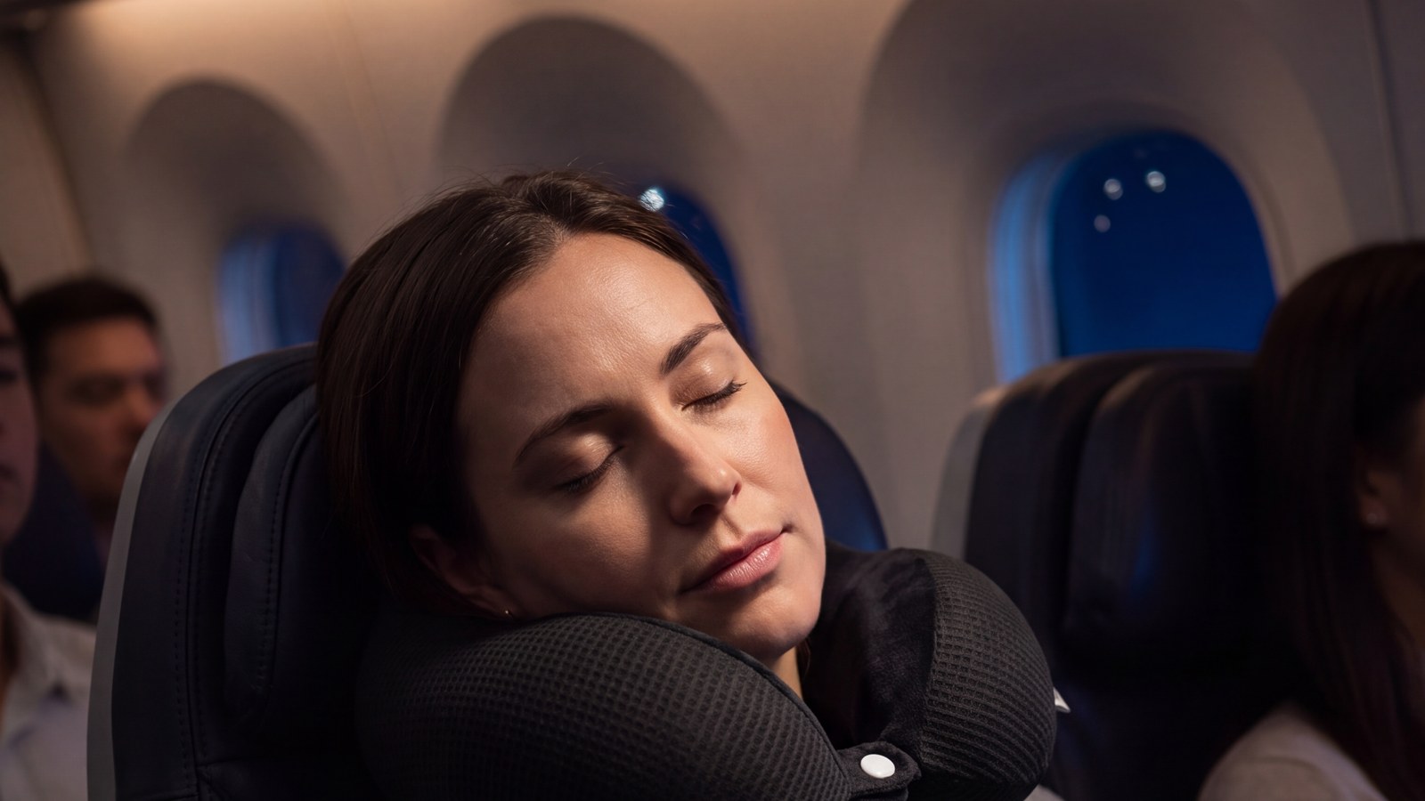 Пассажирка спит в кресле самолёта в подушке для шеи NIERA